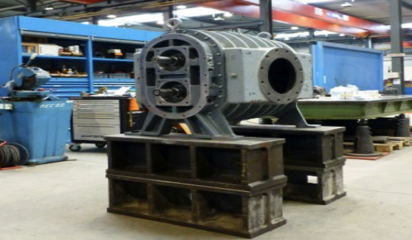 Technician inspecting and repairing industrial blower system in maintenance workshop