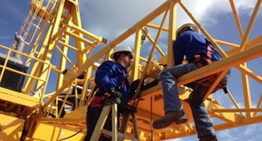 Inspector performing crane structural inspection and load testing at an industrial site