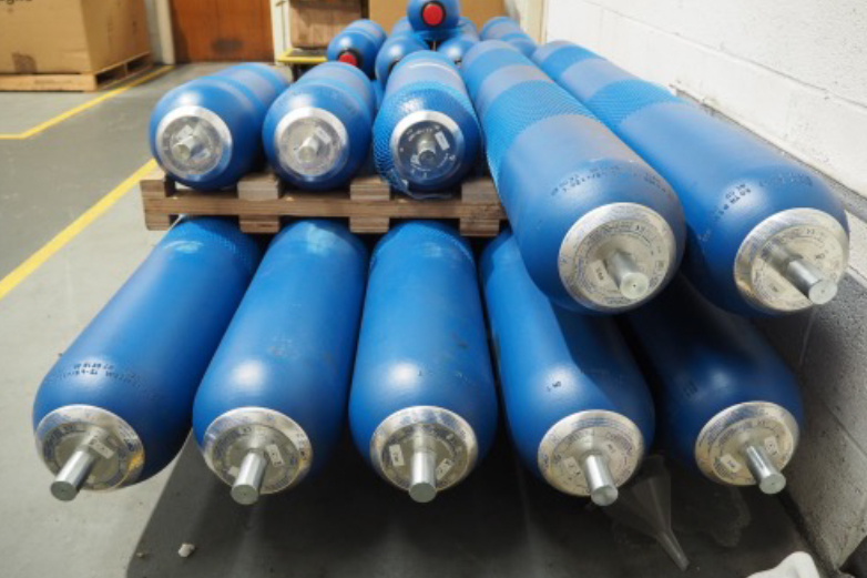Technician performing hydraulic accumulator inspection and pressure testing in workshop