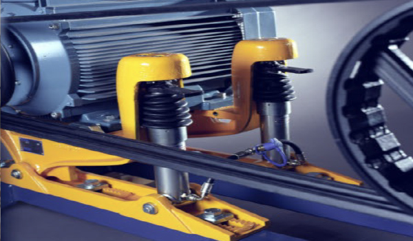 Technician adjusting hydraulic belt tensioning system on industrial motor drive assembly