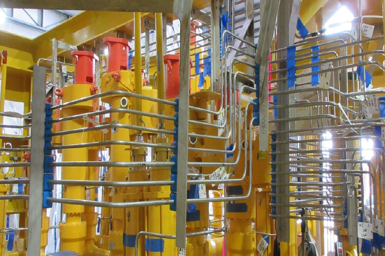 Technicians performing small-bore tubing and piping installation on subsea hydraulic equipment
